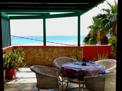 a table and chairs on a patio with a view of the ocean at Ibiscus Penthouse in Santa Maria