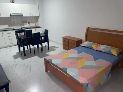 a bedroom with a bed and a kitchen with a table at T0 Brisa Tropical in Sal Rei