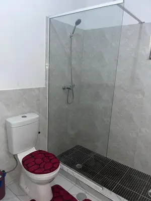 a bathroom with a shower and a toilet with a red seat at T0 Brisa Tropical in Sal Rei