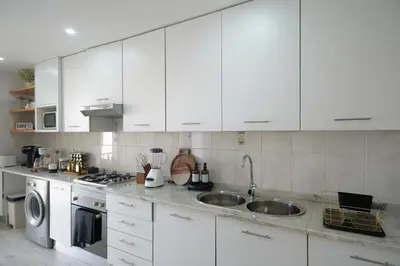 a white kitchen with a sink and a dishwasher at Empire Home! in Praia