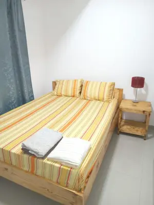 a bed in a room with a lamp and a table at T3 Mindelo in Mindelo