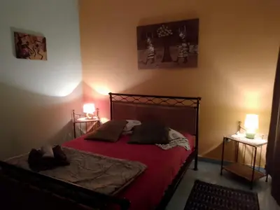 a bedroom with a bed with red sheets and two lamps at Djabraba's kaminhu Double in Vila Nova Sintra