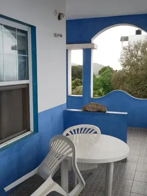 a white table and a chair in front of a blue wall at Djabraba's kaminhu Double in Vila Nova Sintra