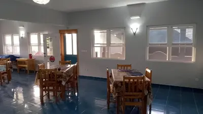 a dining room with tables and chairs and windows at Djabraba's kaminhu Double in Vila Nova Sintra