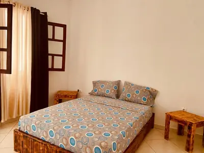 a small bedroom with a bed and a table at MONTROND House in São Filipe