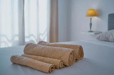 a pile of towels sitting on top of a bed at Tabanka Azul - 2 BdR Cozy and Comfort Apt Near UN in Praia