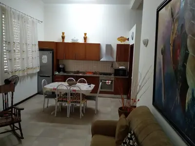 a living room with a table and a kitchen at Apartamento T3 em Alto Miramar in Mindelo