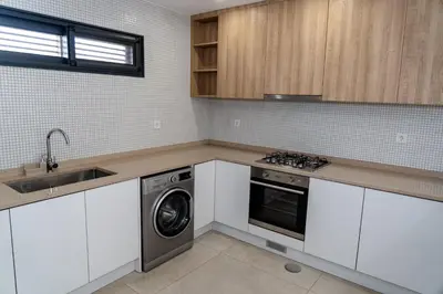 a kitchen with white cabinets and a washing machine at o som das ondas in Praia