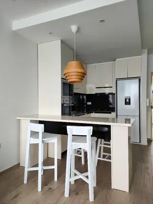 a kitchen with white cabinets and a white island with stools at Casa Nova in Ribeira Grande