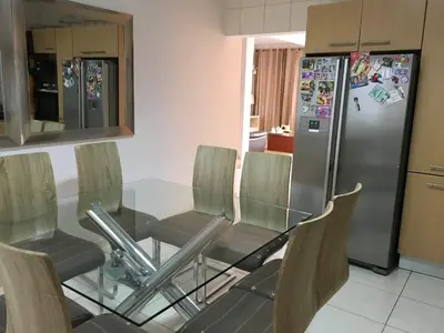 a kitchen with a glass table and a refrigerator at Duplex Avenida Ilhéu Santa Maria, Palmarejo in Praia