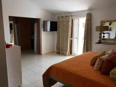 a bedroom with a bed with an orange blanket at Duplex Avenida Ilhéu Santa Maria, Palmarejo in Praia