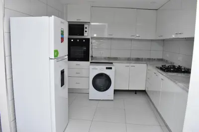 a white kitchen with a washer and dryer in it at Modern 2 bedroom apartment in Achada Santo António Praia'' Perto praca Di Nos