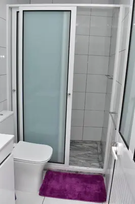a bathroom with a shower with a toilet and a purple rug at Modern 2 bedroom apartment in Achada Santo António Praia'' Perto praca Di Nos