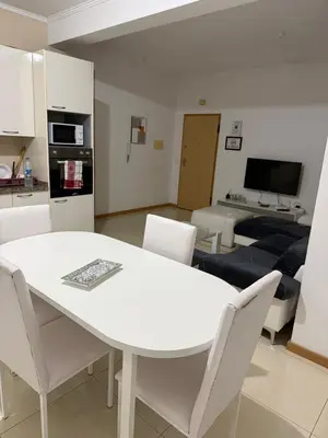 a kitchen and living room with a white table and chairs at Gamboa t2 in Praia