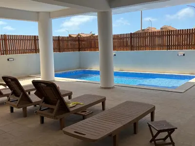 a patio with chairs and a swimming pool at JoLi Beach Apartments with Shared Pool in Santa Maria