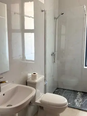 a white bathroom with a toilet and a shower at JoLi Beach Apartments with Shared Pool in Santa Maria