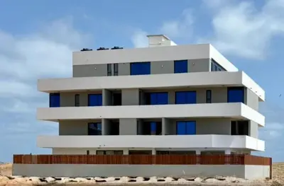 a white building with blue windows on the beach at JoLi Beach Apartments with Shared Pool in Santa Maria