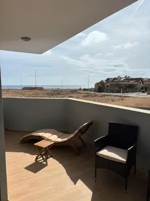 a balcony with a chair and a table and a window at JoLi Beach Apartments with Shared Pool in Santa Maria