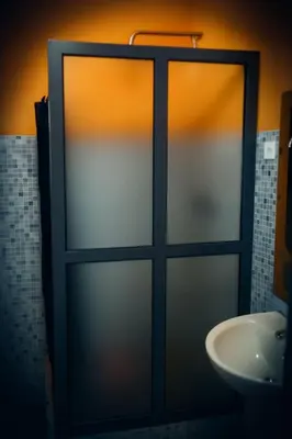 a glass door in a bathroom with a sink at Djabraba's Hiker's Suite in Garça