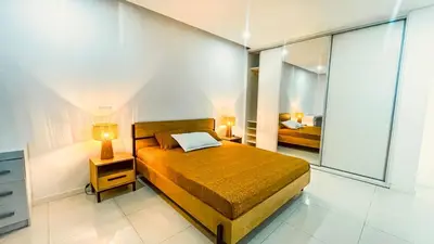 a bedroom with a bed with two lamps and a mirror at Prestige Apartment in Praia