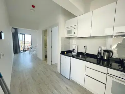 a kitchen with white cabinets and a wooden floor at T1 Espaçoso e aconchegante no Medsal Residence in Prainha