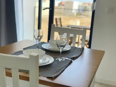 a wooden table with two wine glasses on it at T1 Espaçoso e aconchegante no Medsal Residence in Prainha