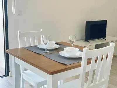 a wooden table with two plates and wine glasses on it at T1 Espaçoso e aconchegante no Medsal Residence in Prainha