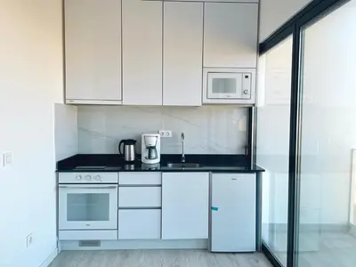 a kitchen with white cabinets and white appliances at T1 panorâmico no Medsal Residence in Santa Maria
