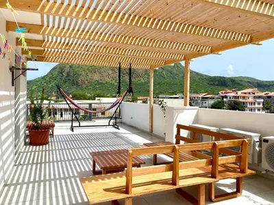 a patio with a bench and a hammock on a roof at Casa Uta in Tarrafal