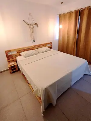 a bedroom with a large bed with white sheets at Kasa surf in Porto Novo