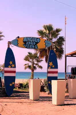 a surfboard on the beach next to some palm trees at Flat 4U in Santa Maria
