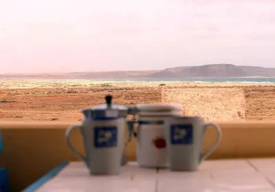 two coffee cups on a window sill looking out at the beach at Flat 4U in Santa Maria