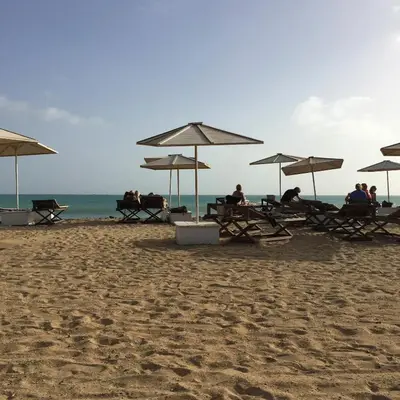 a group of people sitting under umbrellas on a beach at Flat 4U in Santa Maria