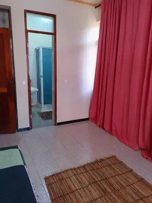 a room with a red curtain and a bathroom at Essencia Sterra in Praia