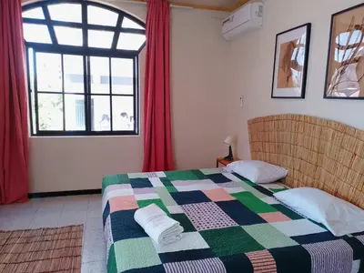 a bedroom with a bed and a large window at Essencia Sterra in Praia