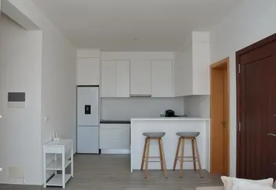 a kitchen with white cabinets and two bar stools at Comfort and Peace in Santa Maria