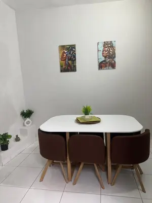 a dining room table and chairs with paintings on the wall at T2 Vacation in Mindelo in Mindelo