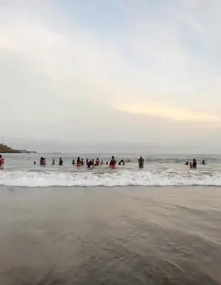 a group of people are in the water at the beach at Condominio atlantico ll in Praia