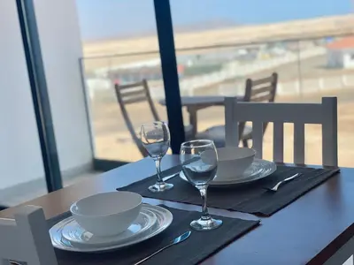 a table with plates and wine glasses on a table with the beach at Studio Medsal in Santa Maria