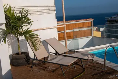 a balcony with two chairs and a potted plant at Fresh One Too Apartment in Praia