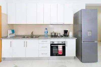 a kitchen with white cabinets and a stainless steel refrigerator at New building - 1 min away from the main road in Santa Maria