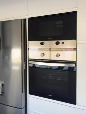 a microwave oven in a kitchen next to a refrigerator at 2-bdr bright apt central street cidadela - LCGR in Praia
