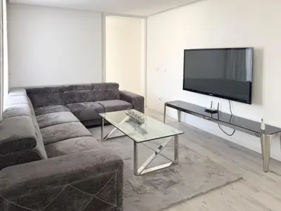 a living room with a couch and a flat screen tv at 2-bdr bright apt central street cidadela - LCGR in Praia