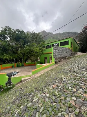 a green building with a stone wall next to a yard at Residencial Palice