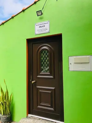 a door to a green building with a sign above it at Residencial Palice