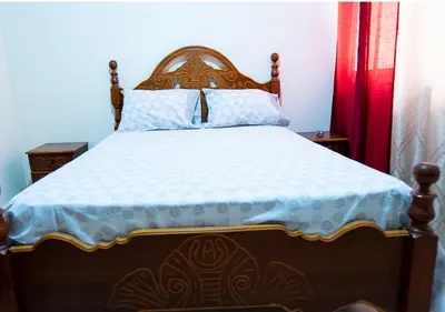 a bed with a wooden headboard in a bedroom at Residencial Mendes in Tarrafal