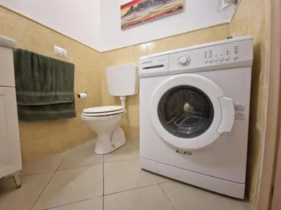 a washing machine in a bathroom with a toilet at T2 Djadsal Bloco Laranja Perto da Praia e Centro in Santa Maria