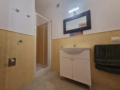 a bathroom with a sink and a shower and a mirror at T2 Djadsal Bloco Laranja Perto da Praia e Centro in Santa Maria