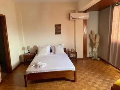 a bedroom with a bed with white sheets and a fan at Residencial P&P in Mindelo