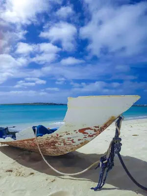 a boat sitting on a beach with the ocean at Casa Albacora in Sal Rei